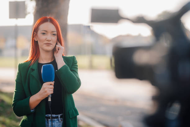 istock Journalist reporting live news holding microphone and adjusting in-ear 2187810133