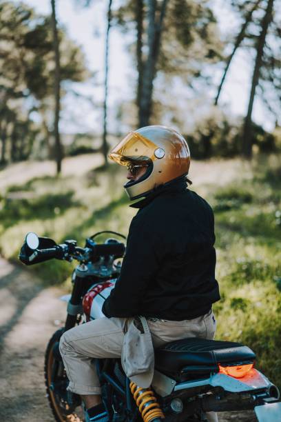 istock Motorcyclist in a golden helmet on a forest path. 2187810644
