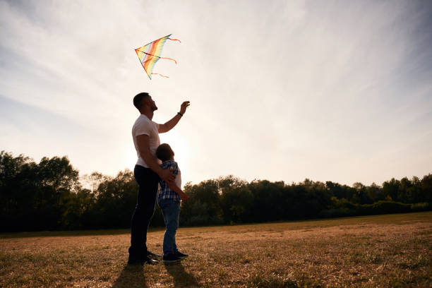 istock Father and son are with kite on the field, illuminated by sunlight 2187811681
