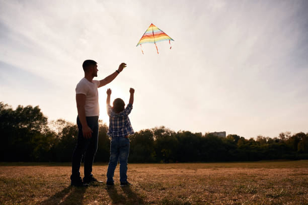 istock Father and son are with kite on the field, illuminated by sunlight 2187811685