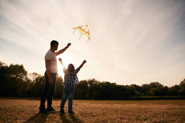 istock Father and son are with kite on the field, illuminated by sunlight 2187811687