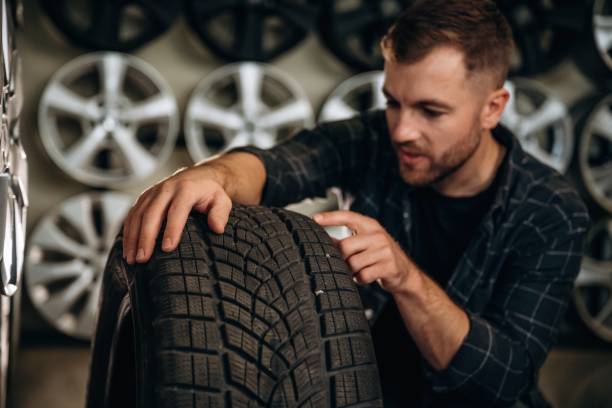 istock Sitting, professional man worker is maintenance station with tires, wheels 2187818324