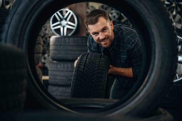 istock Looking through the hole in tire. Man worker is maintenance station with wheels 2187818512