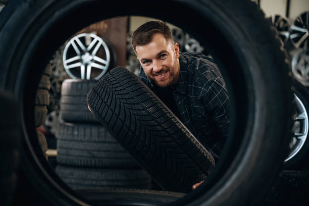 istock Looking through the hole in tire. Man worker is maintenance station with wheels 2187818513
