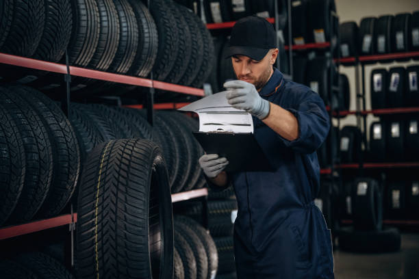 istock Black colored notepad, information, documents. Man worker is maintenance station with tires, wheels 2187819073