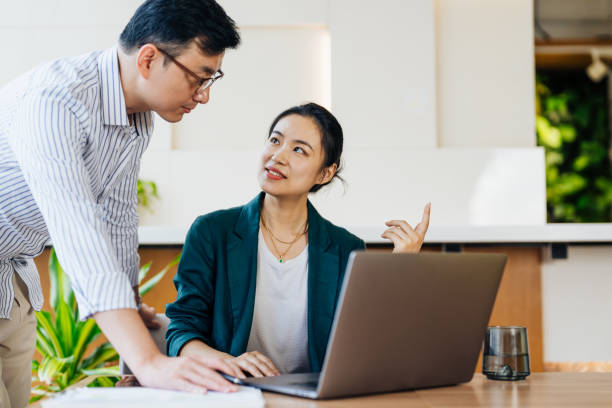 istock Confident Asian business team working together using a laptop at the office and smiling. 2187824533