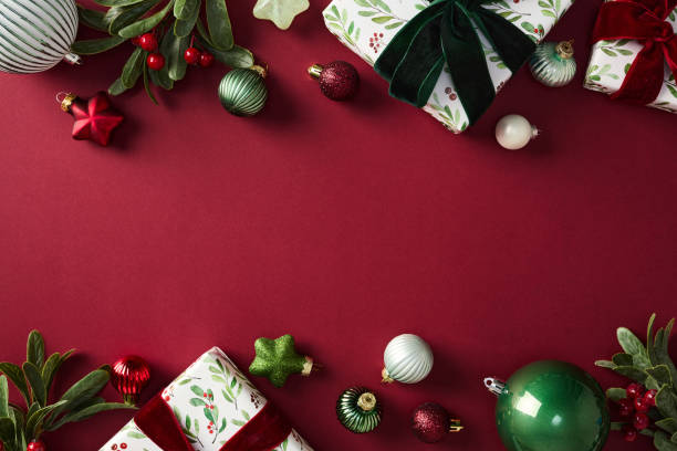 istock Stylish chic Christmas decorations and gifts on red backdrop, featuring baubles, bells, and wrapped presents. Perfect for holiday-themed projects and seasonal marketing 2187826655
