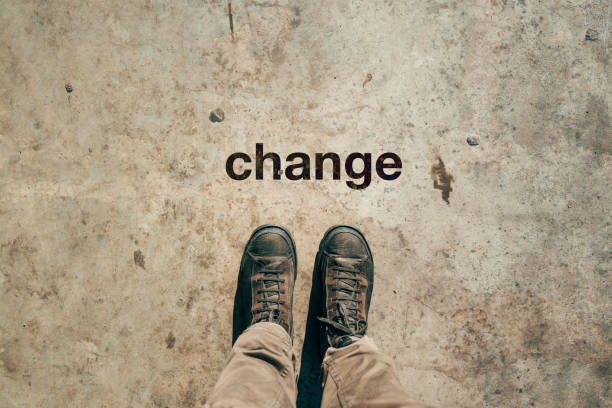 istock Feet in boots from above with word Change printed on sidewalk 2187827706