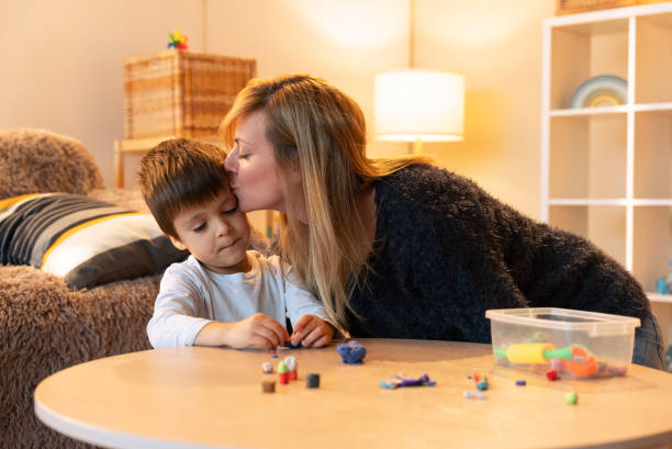 istock Loving mother kissing her son while playing with clay at home 2187827997