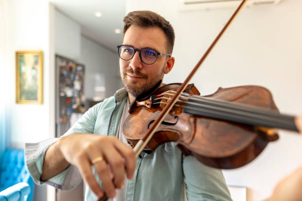 istock Man Playing Violin With Focused Expression in Bright Room 2187829365
