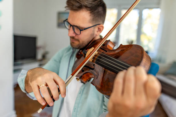 istock Man Playing Violin in Bright Room with Focused Expression and Skill 2187829554