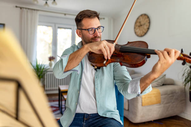 istock Man Playing Violin in a Stylish Modern Living Room Setting 2187829555