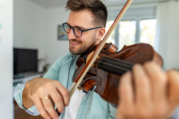 istock Smiling Man Playing Violin Indoors With Natural Light And Glasses 2187829559