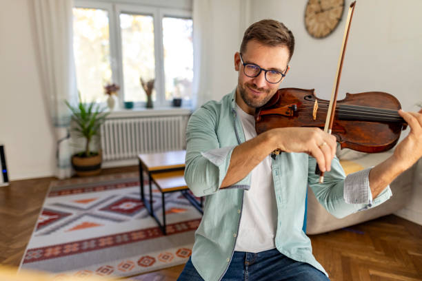 istock Man Playing Violin in Cozy Living Room with Natural Light 2187829608