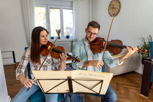 istock Couple Playing Classical Music on Violins in Living Room Setting 2187829891