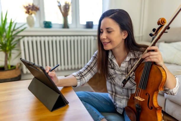 istock Young Woman Practicing Violin With Digital Tablet in Cozy Living Room 2187830167