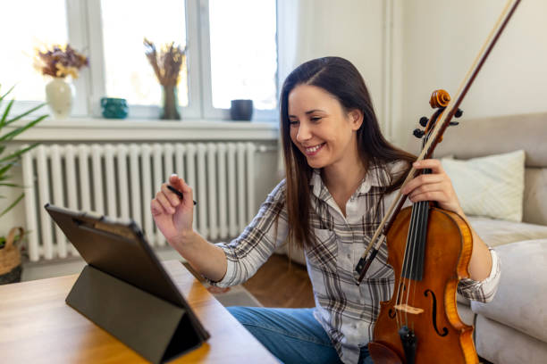 istock Woman Practicing Violin Using Tablet for Online Music Lesson at Home 2187830168