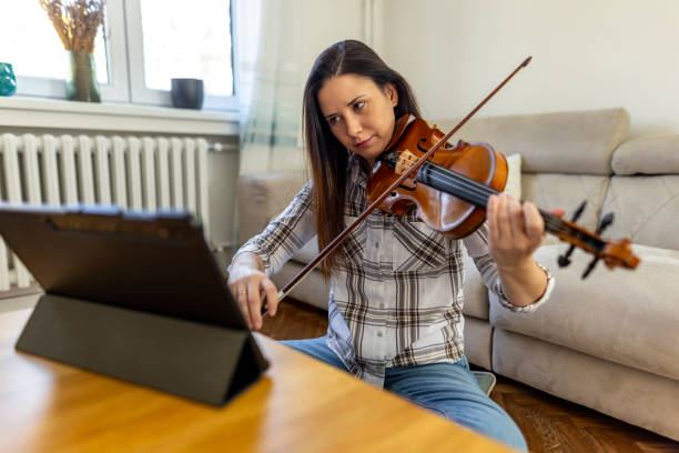 istock Woman Practicing Violin At Home Using a Digital Tablet for Guidance 2187830353