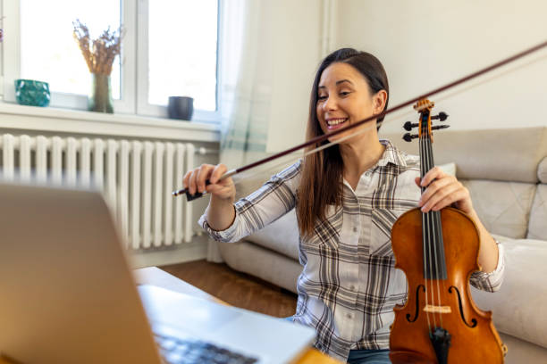 istock Woman Learning Violin Online Through Virtual Music Lesson at Home 2187830496