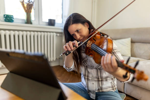 istock Focused Woman Practicing Violin at Home with Digital Tablet 2187830500