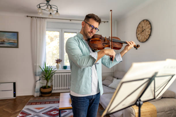 istock Man Practicing Violin at Home in Peaceful Living Room Setting 2187831376