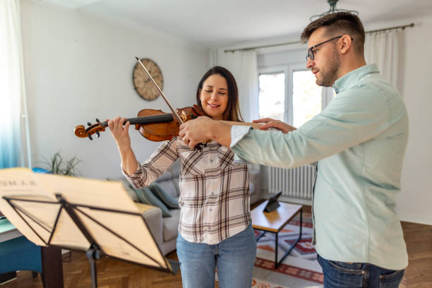 istock Young Woman Learning to Play Violin With Instructor at Home 2187831696