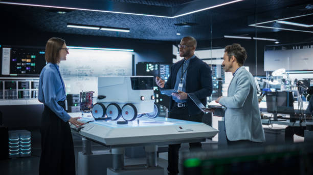 istock Diverse Team of Industrial Specialists Working on Remotely Controlled Robot, Using a Laptop. Young Male and Female Engineers Discussing an Autonomous AI Delivery Assistant Prototype, Brainstorming 2187840479