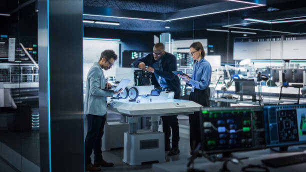istock Industrial Robotics Specialists Working on a Mobile Robot, Using a Tablet Computer and Laptop. Black Male Engineer In a Lab Discussing an Automated AI Robotic Delivery Assistant with His Young Team 2187840648