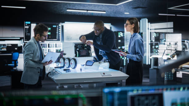 istock Diverse Team of Industrial Specialists Working on Remotely Controlled Mobility Robot in a Research Facility. Engineers Testing and Fixing Detection Cameras While Using Tablet and Laptop 2187840862