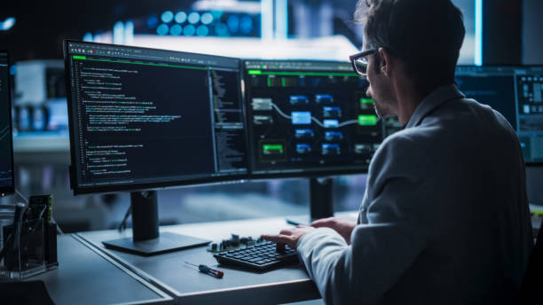 istock Back View of a Young Engineer Working on Computer in a Technological Office Environment. Male Programmer Writing Software Code for a Blockchain Project, Developing Backend System 2187841006