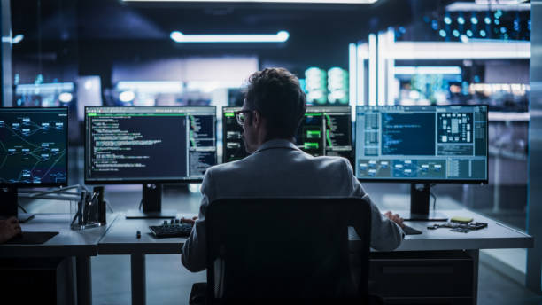 istock Back View of a Young Engineer Working on Computer in a Technological Office Environment. Male Programmer Writing Software Code for a Blockchain Project, Developing Backend System 2187841176