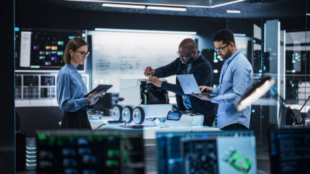 istock Diverse Team of Industrial Robotics Specialists Gathered Around a Table With a Mobile Robot. Engineers Discussing an Automated Robotic Delivery Assistant with Artificial Intelligence 2187841876