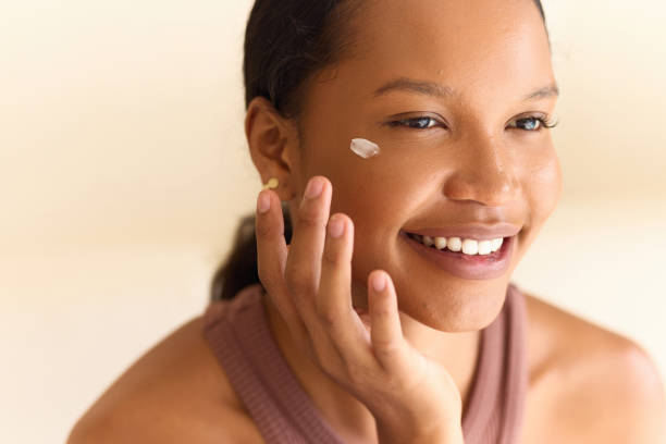 istock Smiling Woman Applying Face Cream in Natural Light Setting 2187844461