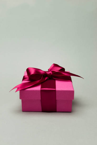 A beautifully wrapped pink gift box tied with a satin ribbon on a neutral background. The image represents celebration, gifting, and special occasions with a touch of elegance.