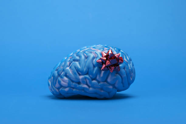Blue brain with a gift bow on a plain blue background. Symbolizing 'Blue Monday' the saddest day of the year, with a hint of irony