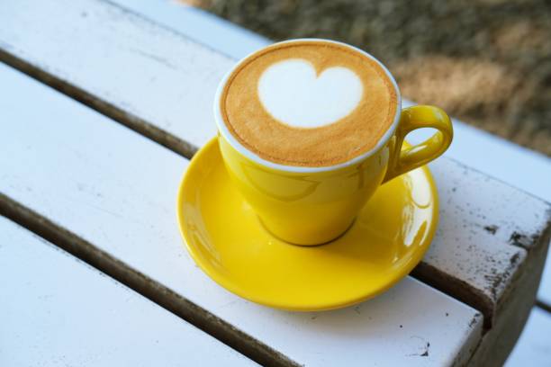 istock A vibrant yellow cup of latte art on a white table. 2187847720