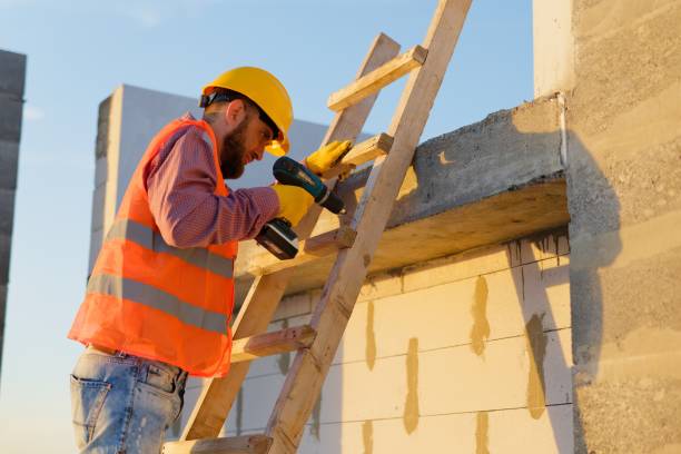 istock Construction worker using cordless drill on wooden ladder at building site 2187850752