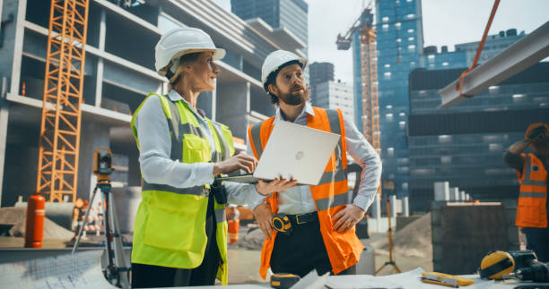 istock Female Civil Engineer and an Architect Having a Conversation During an Outdoors Meeting at a Building Site Area. Specialists Using a Laptop Computer to Discuss Details on a Construction Plan 2187852318