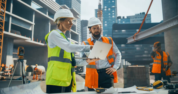 istock Female Civil Engineer and an Architect Having a Conversation During an Outdoors Meeting at a Building Site Area. Specialists Using a Laptop Computer to Discuss Details on a Construction Plan 2187852333