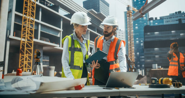 istock Professional Female Civil Engineer and a Construction Manager Having a Meeting to Discuss Development of a Real Estate Building. Specialist Using Tablet Computer to Oversee the Project Plans 2187852869