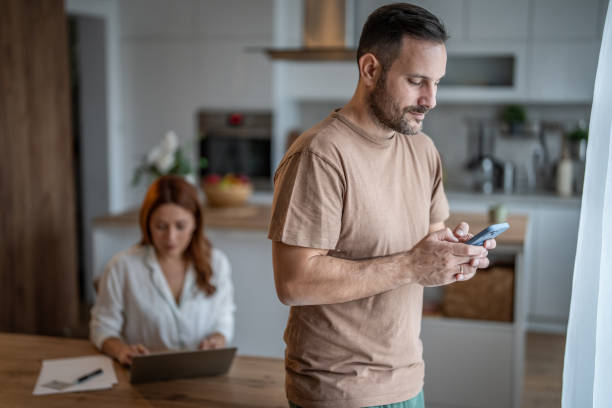 istock Digital dynamics - Man in focus with phone, wife in background with laptop 2187855625