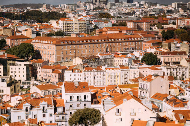 Explore the vibrant cityscape of Lisbon's historic district, featuring iconic red rooftops, traditional architecture, and lush greenery. Experience the charm and cultural richness of Portugal's capital city.