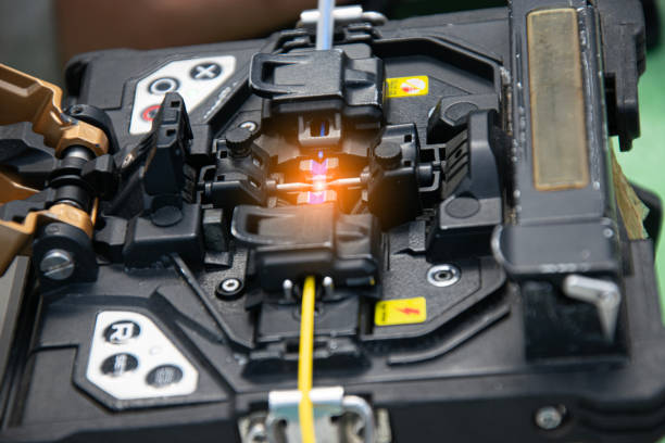 The technician is connecting the fiber optic cable with a tool.