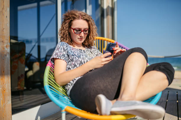 Beautiful young woman using a phone while sitting on the beach in Albena in Bulgaria.