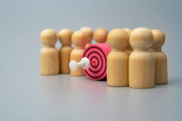 istock A target with a dart in the center surrounded by wooden figures. 2187859631