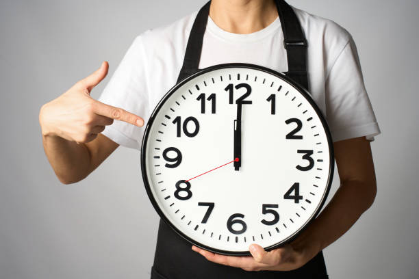 istock Cooking deadline concept. Woman chef in apron holding clock, white background with copy space 2187859756