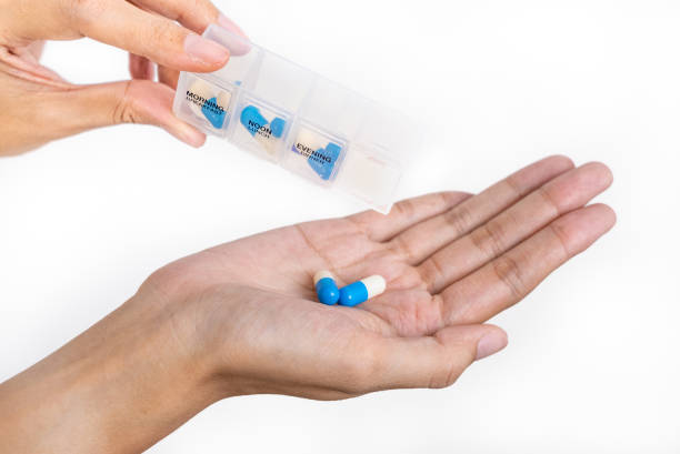 istock Close up shot, Female hand holding capsules with pills planner on white isolate background, taking medicine for headache, abdominal pain or taking vitamins, sedatives, health care concept. 2187859829