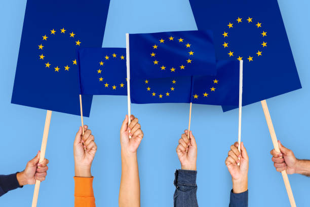istock Diverse Hands Holding European Union Flags in Protest Against Blue Background 2187860644