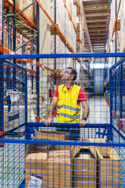 istock Warehouse worker pushing cart and looking up at shelves 2187860770