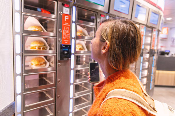 istock Woman using automated food vending machine while smiling 2187863359
